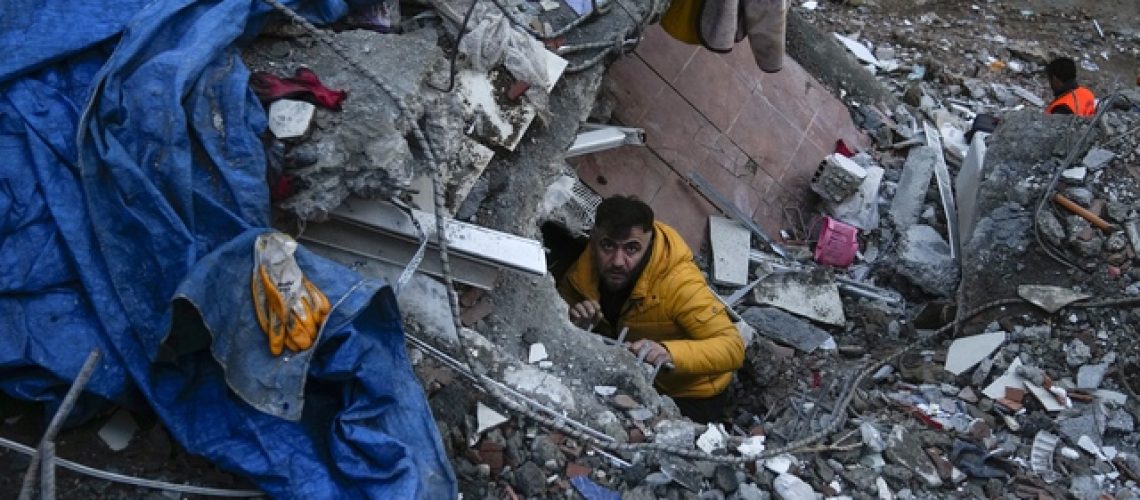 A man searches for people in a destroyed building in Adana, Turkey, Monday, Feb. 6, 2023. A powerful quake has knocked down multiple buildings in southeast Turkey and Syria and many casualties are feared. (AP Photo/Khalil Hamra)